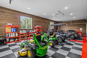 A four-car garage featuring checkered flooring, windows, and smooth horizontal ranchwood Eastern cedar siding.