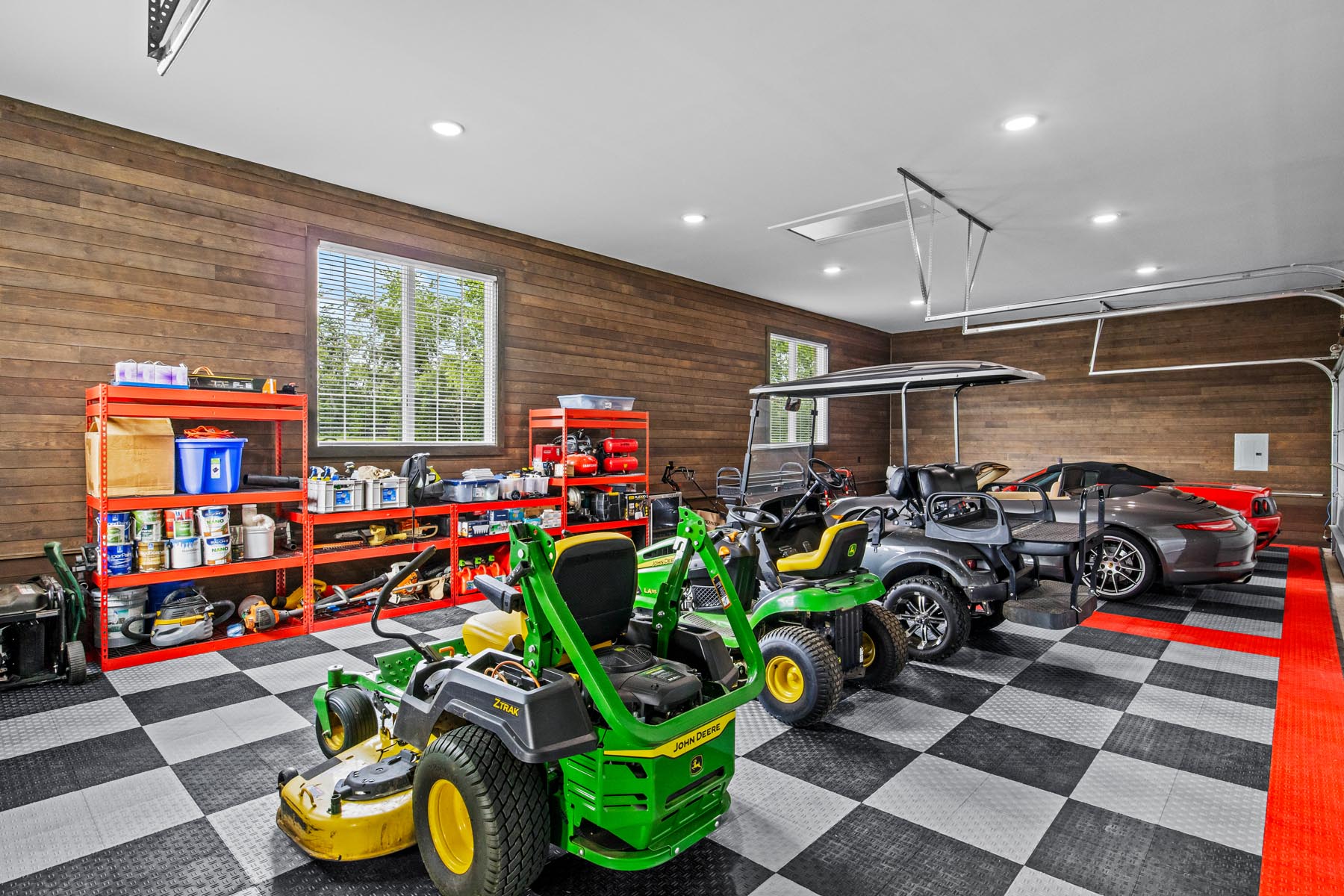 A four-car garage featuring checkered flooring, windows, and smooth horizontal ranchwood Eastern cedar siding.