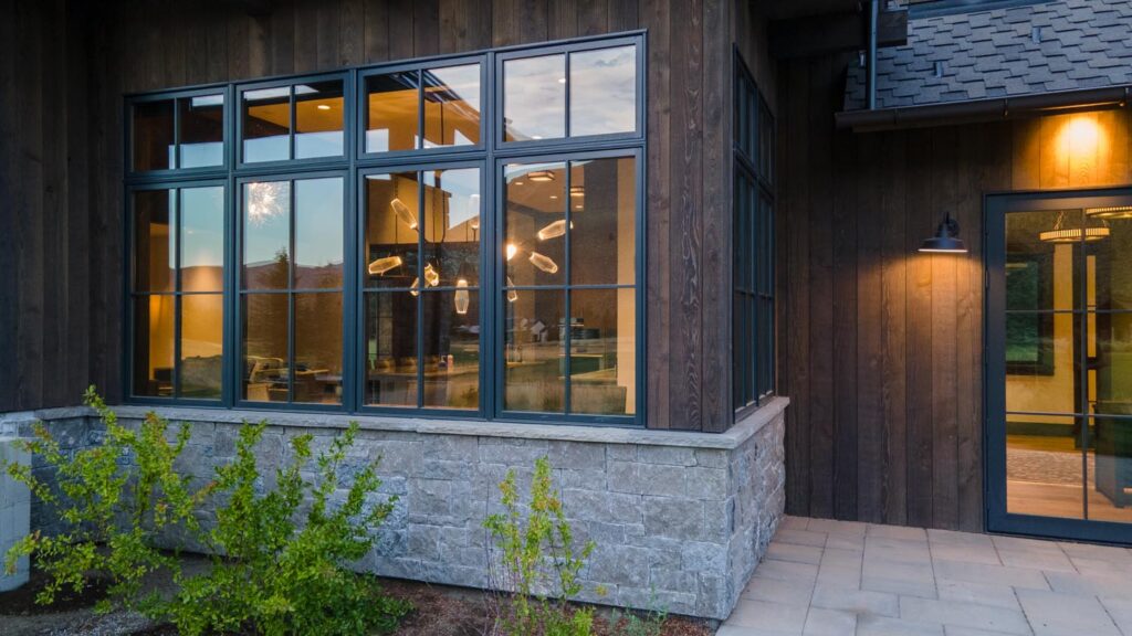 Close-up of natural stone masonry wainscoting providing a protective dry separation for the ranchwood Western natural wood vertical siding on a custom mountain home. natural stone wainscoting.