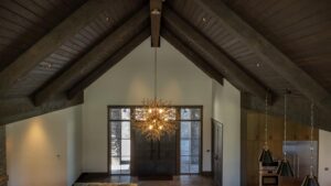 Vaulted interior ceiling of a luxury Great Room wrapped in ranchwood Western Douglas Fir featuring an elegant branch chandelier.