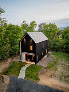 High-angle daylight view of the Wild Azalea House showing the metal standing-seam roof, stepping stone walkway, and prefinished wood siding engineered for mountain climates.