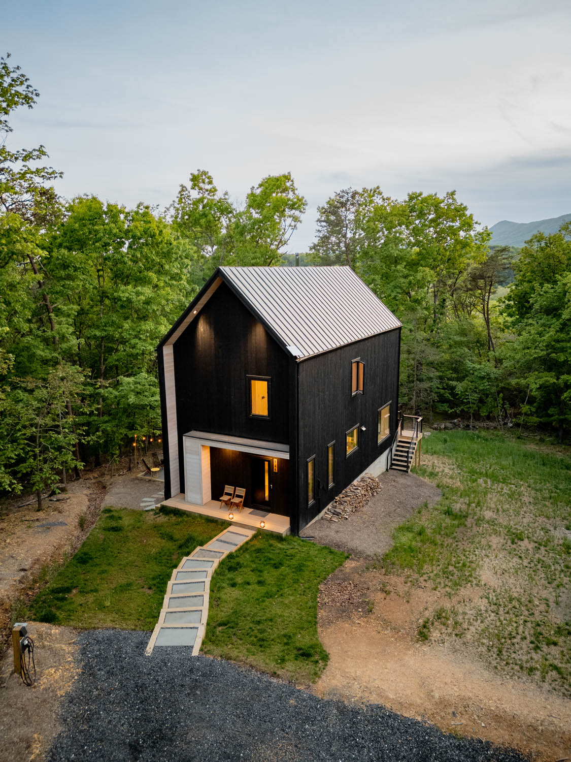 High-angle daylight view of the Wild Azalea House showing the metal standing-seam roof, stepping stone walkway, and prefinished wood siding engineered for mountain climates.