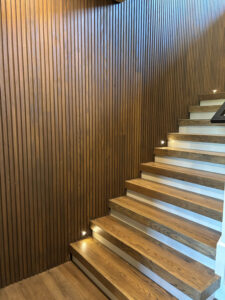 Interior stairwell accent wall featuring custom triple-fluted Thermally Modified Southern Yellow Pine wood paneling in AquaFir Cascade.