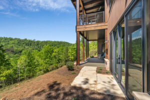 Covered back patio and upper balcony showing vertical thermally modified Southern Yellow Pine wood siding on a hillside elevation.