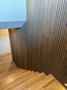 View looking down a staircase showing continuous custom fluted Southern Yellow Pine wood siding transitioning from the main level to the lower level.