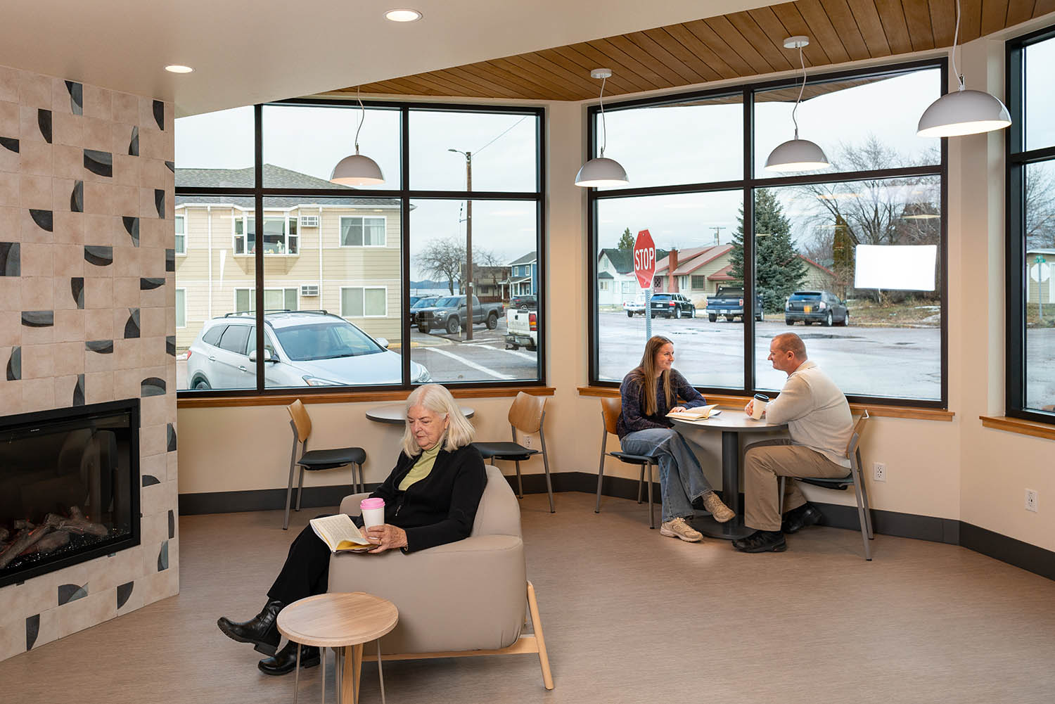 Library seating area next to a fireplace showing AquaFir Light Brown ceiling panels with people lifestyle