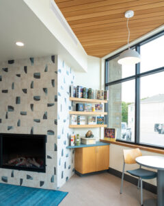 Library seating area next to a fireplace wallpaper showing AquaFir Light Brown ceiling panels over built-in cabinetry.