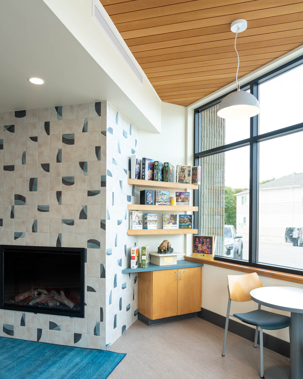 Library seating area next to a fireplace wallpaper showing AquaFir Light Brown ceiling panels over built-in cabinetry.