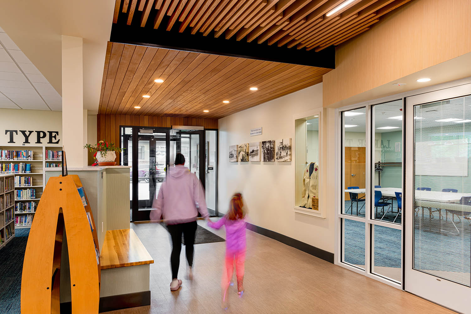 Interior entry hallway showing smooth AquaFir Light Brown wood ceiling panels continuing from the exterior entry soffit.