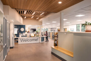Reception counter at Polson Public Library beneath a CVG Douglas Fir tongue-and-groove ceiling with recessed lighting fixtures.
