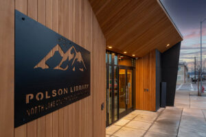 Exterior elevation of the Polson Public Library entrance showing vertical AquaFir Light Brown Tex Gap siding behind steel mountain logo signage.