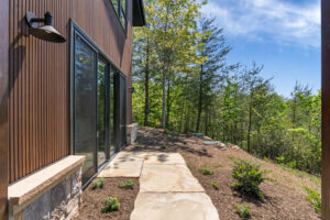 Exterior wall with black gooseneck light showing custom fluted Southern Yellow Pine wood siding texture next to a sliding glass door.